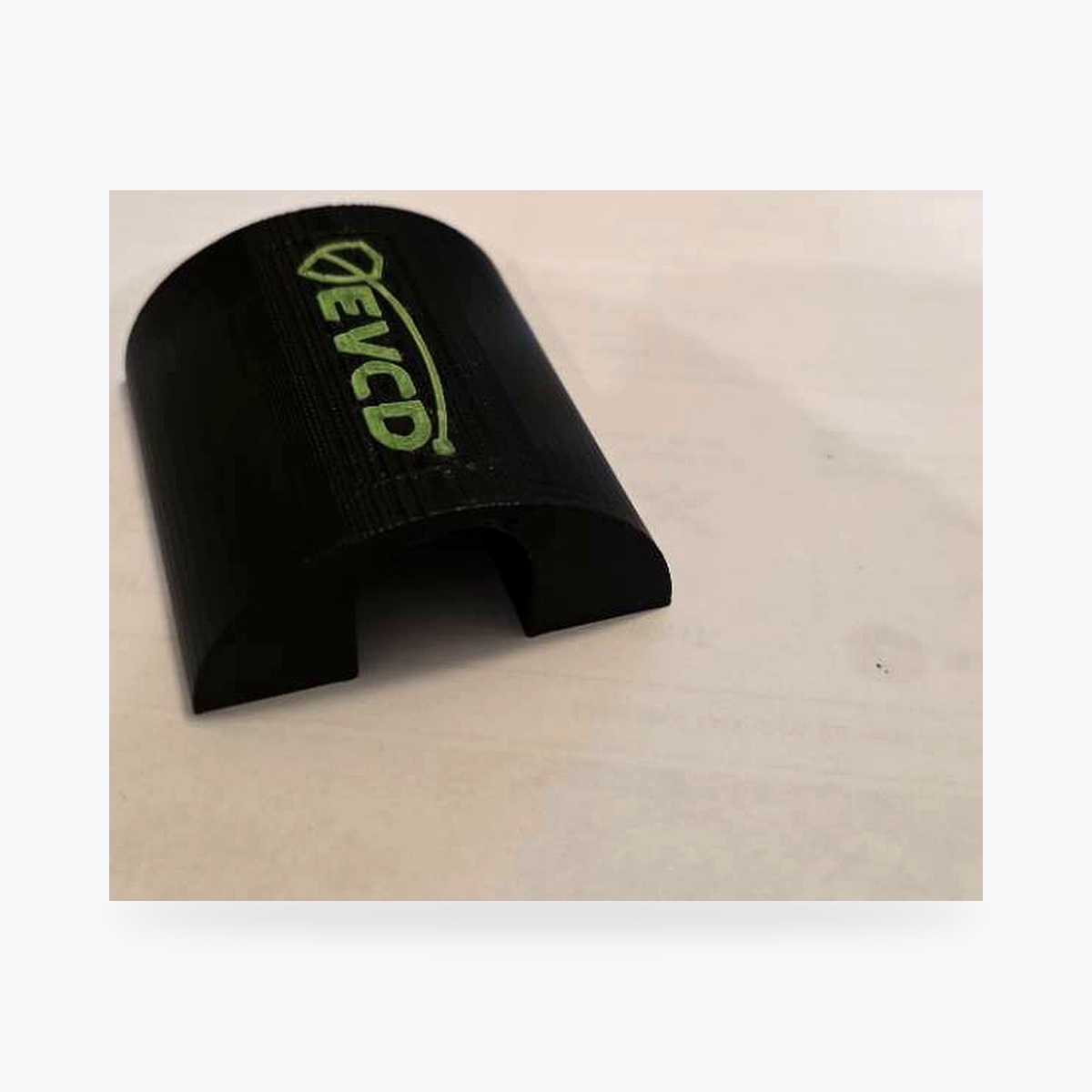 EVCD Arc Solo resting flat on its base with the single cable opening on the ground and the green logo facing up